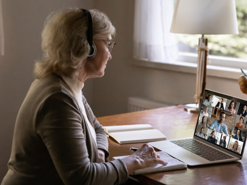 Older,Mature,Businesswoman,In,Headphones,Holding,Online,Video,Call,Conference